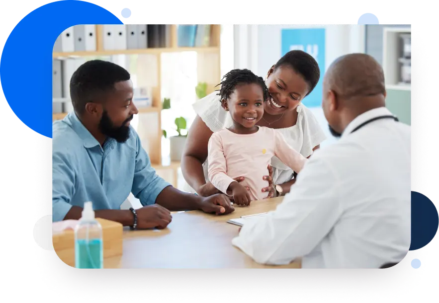 A mother and father holding their happy daughter in front of a doctor